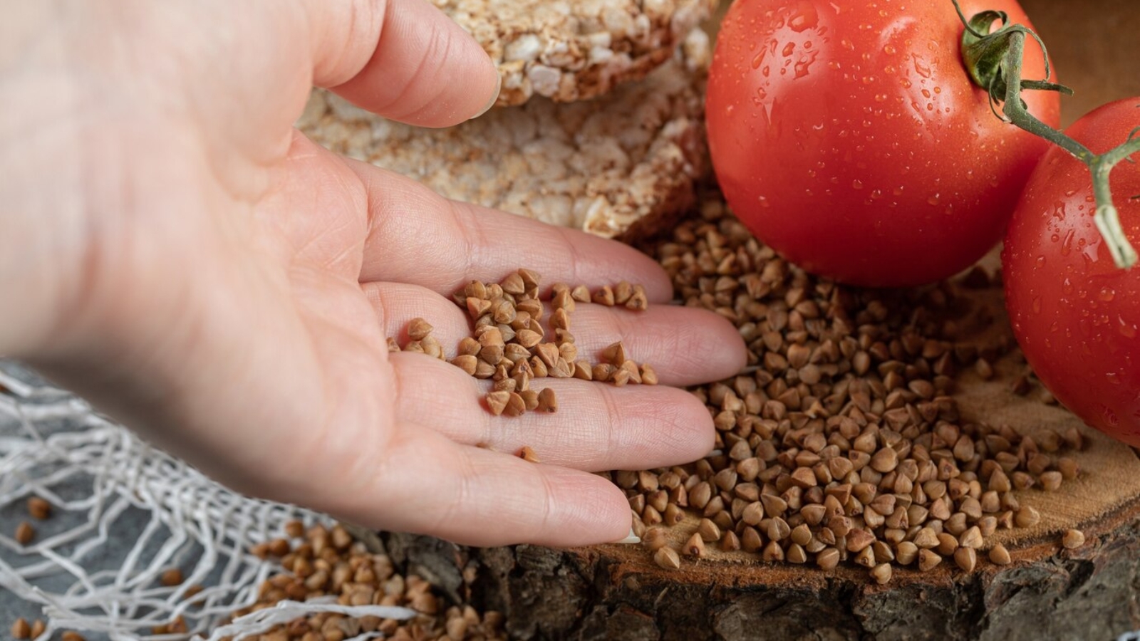 female-hand-holding-raw-buckwheat-from-wooden-piece_114579-25317